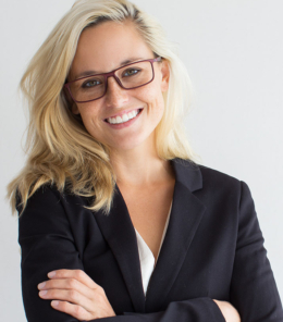 Studio portrait of successful young Caucasian businesswoman wearing costume and glasses standing with folded arms, looking at camera and smiling
